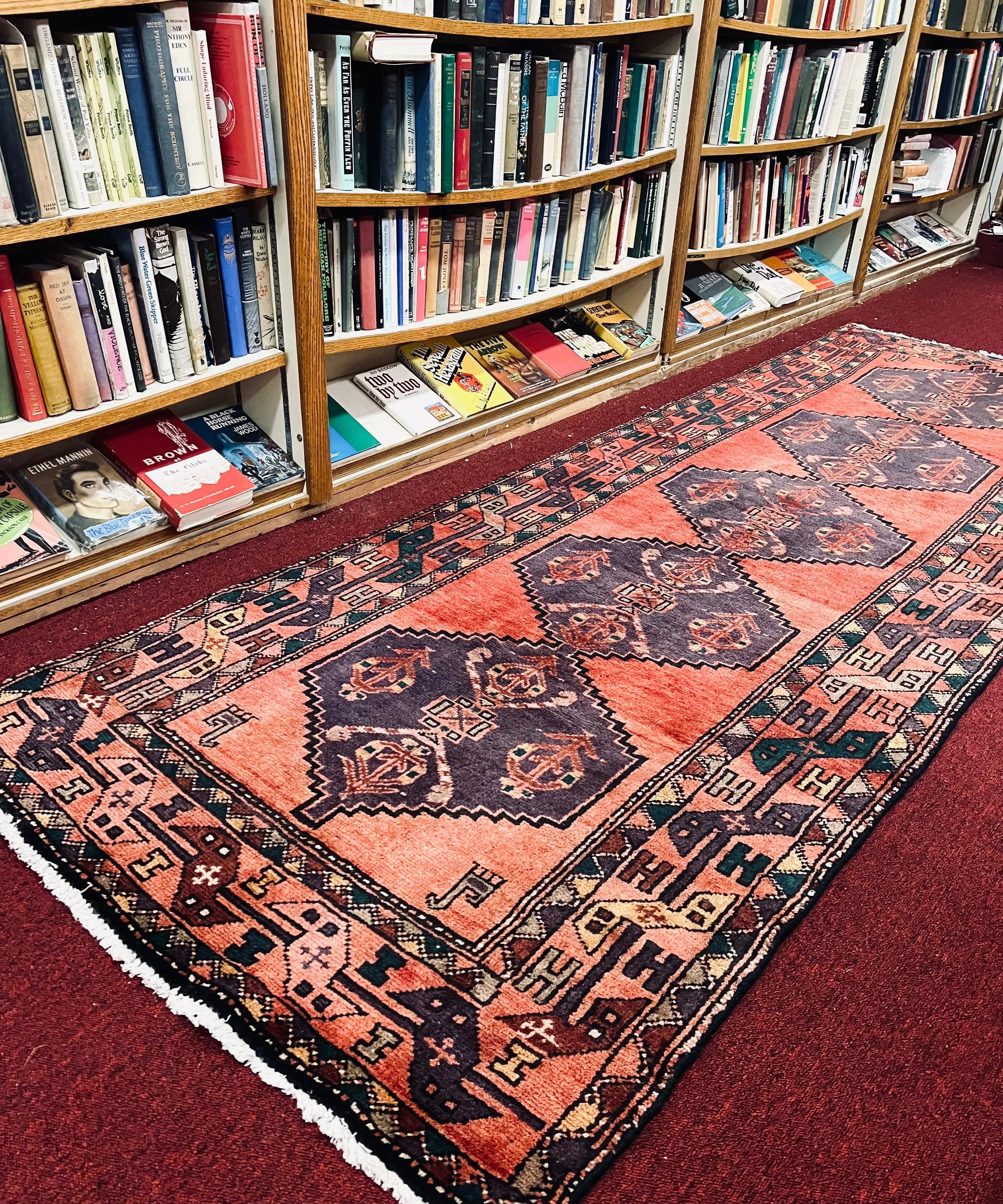 Vintage Persian-style runner rug with red field, navy medallions, and cream fringe