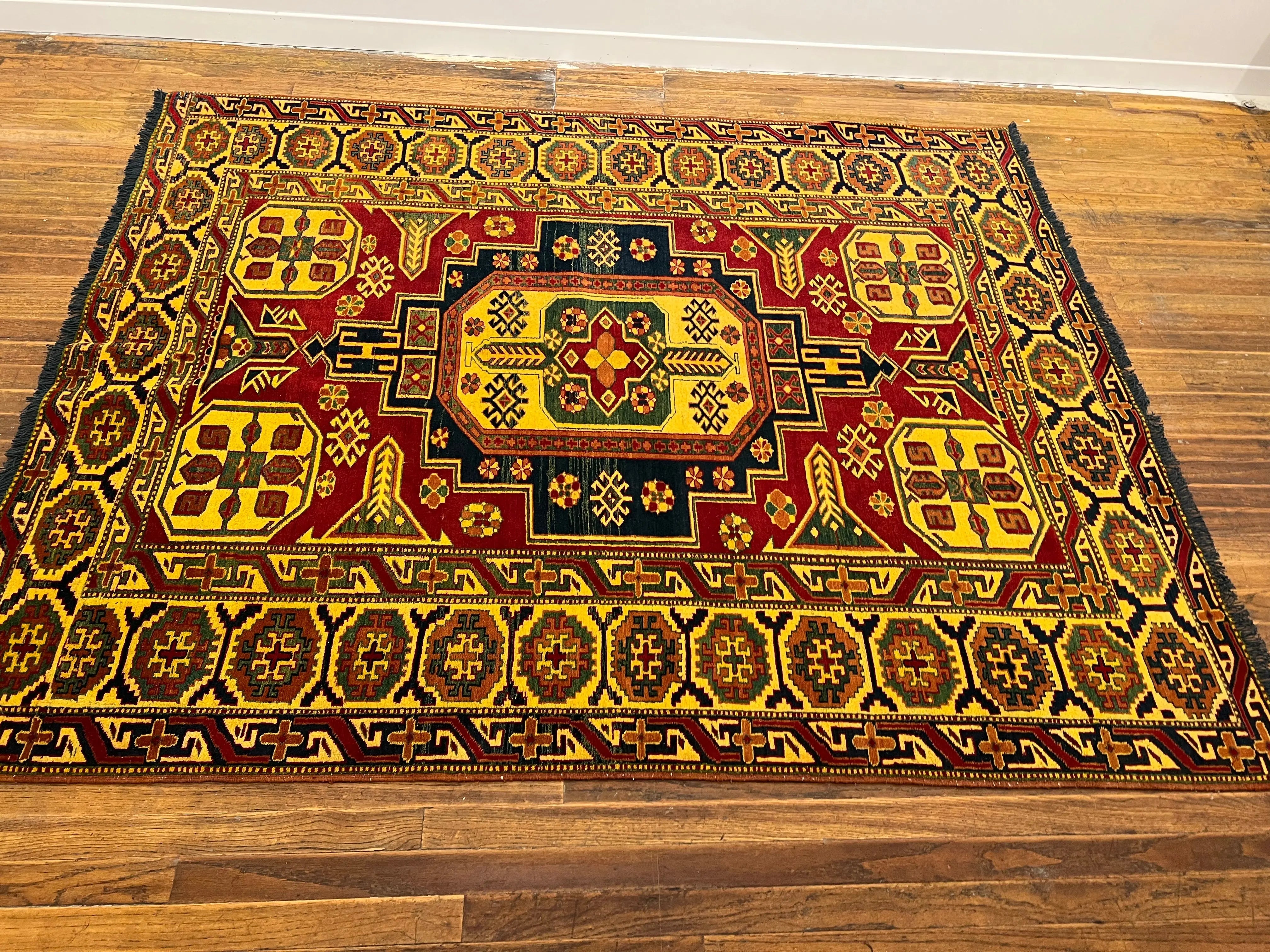 Kazak area rug with bold geometric medallion in gold, red, and navy