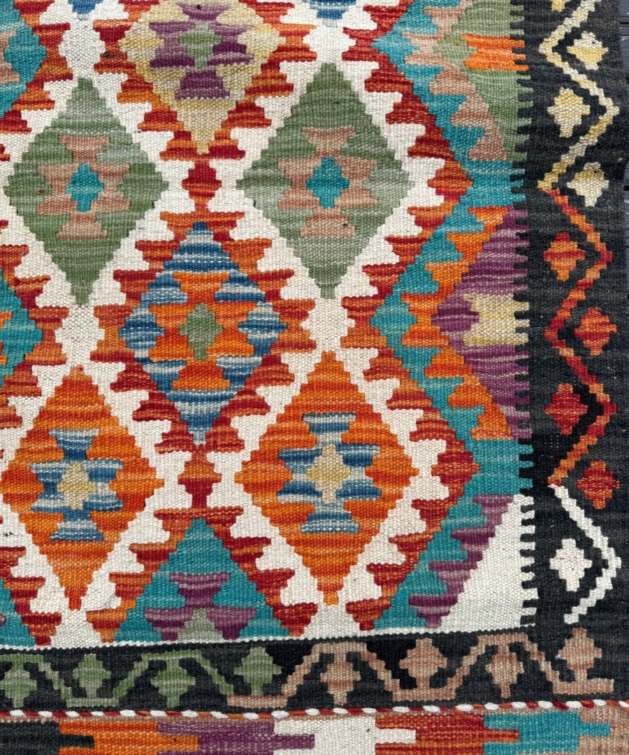 Kilim runner rug close-up with diamond pattern and multicolor zigzag border
