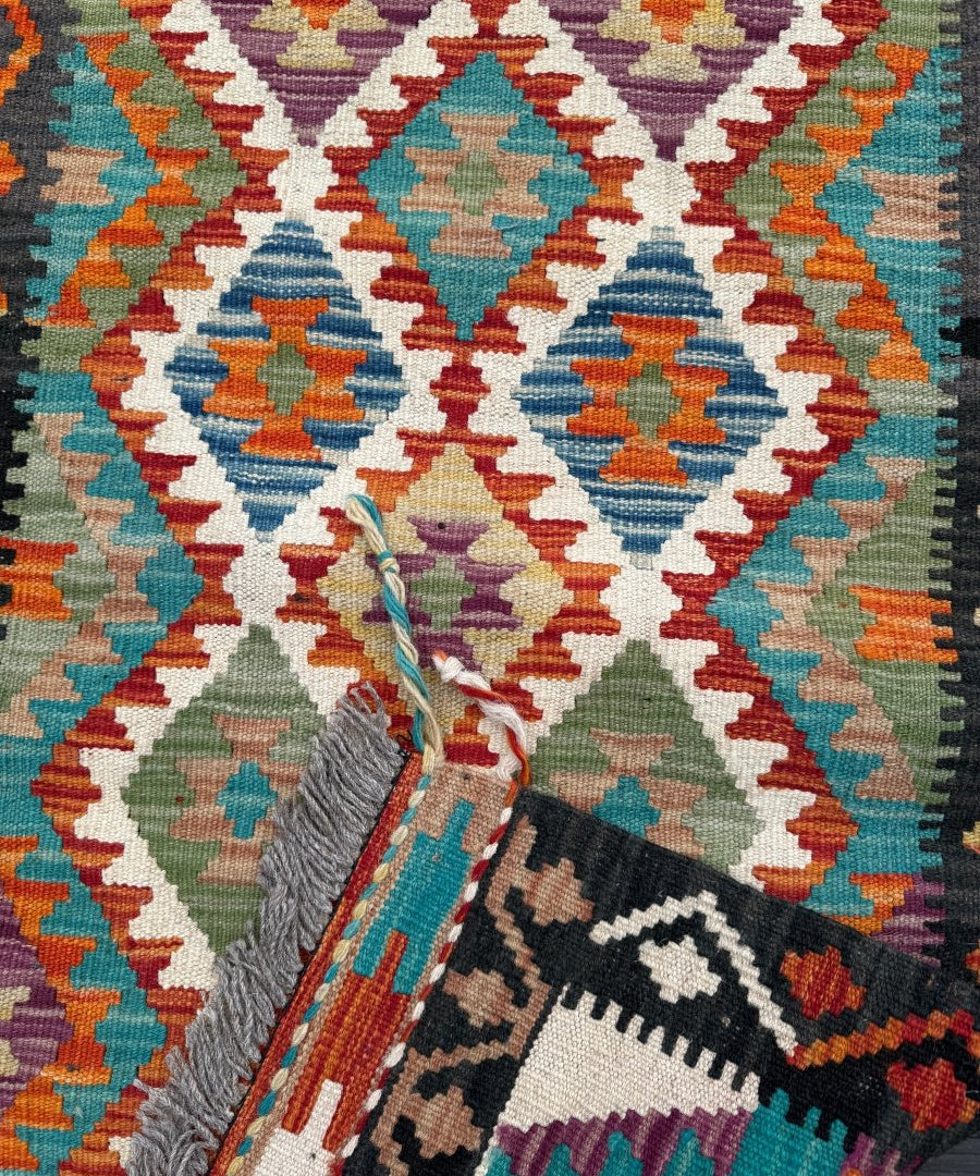 Kilim runner rug corner detail with patterned weave and braided fringe
