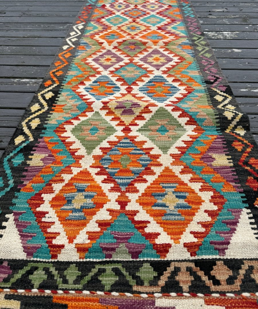 Kilim runner rug with central diamond medallion in teal, orange, red, and cream