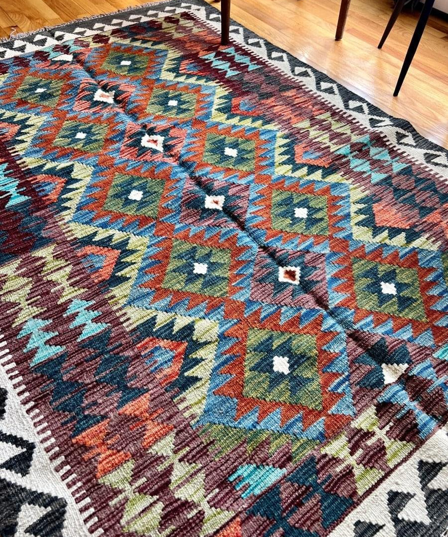 Afghan kilim rug with geometric border, multicolor diamonds, and fringe edges