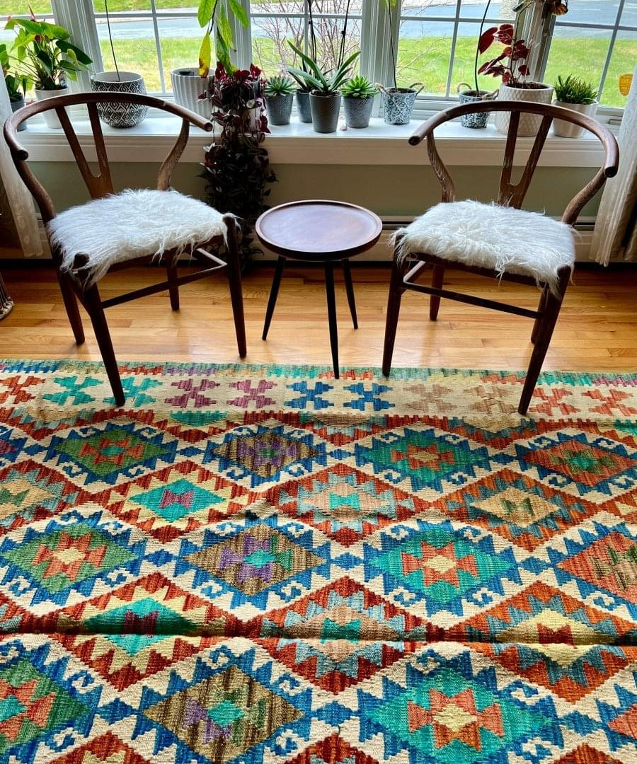 Kilim rug on floor with turquoise, red, blue, and green geometric diamond motifs