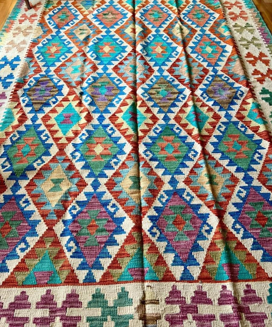 Kilim rug laid flat with turquoise, orange, blue, and red diamond rows