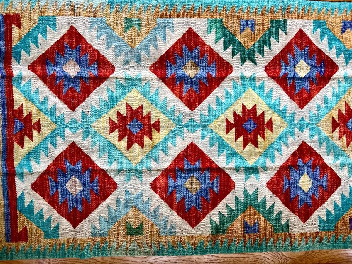 Turquoise kilim runner rug with diamond and star motifs in red, navy, and yellow