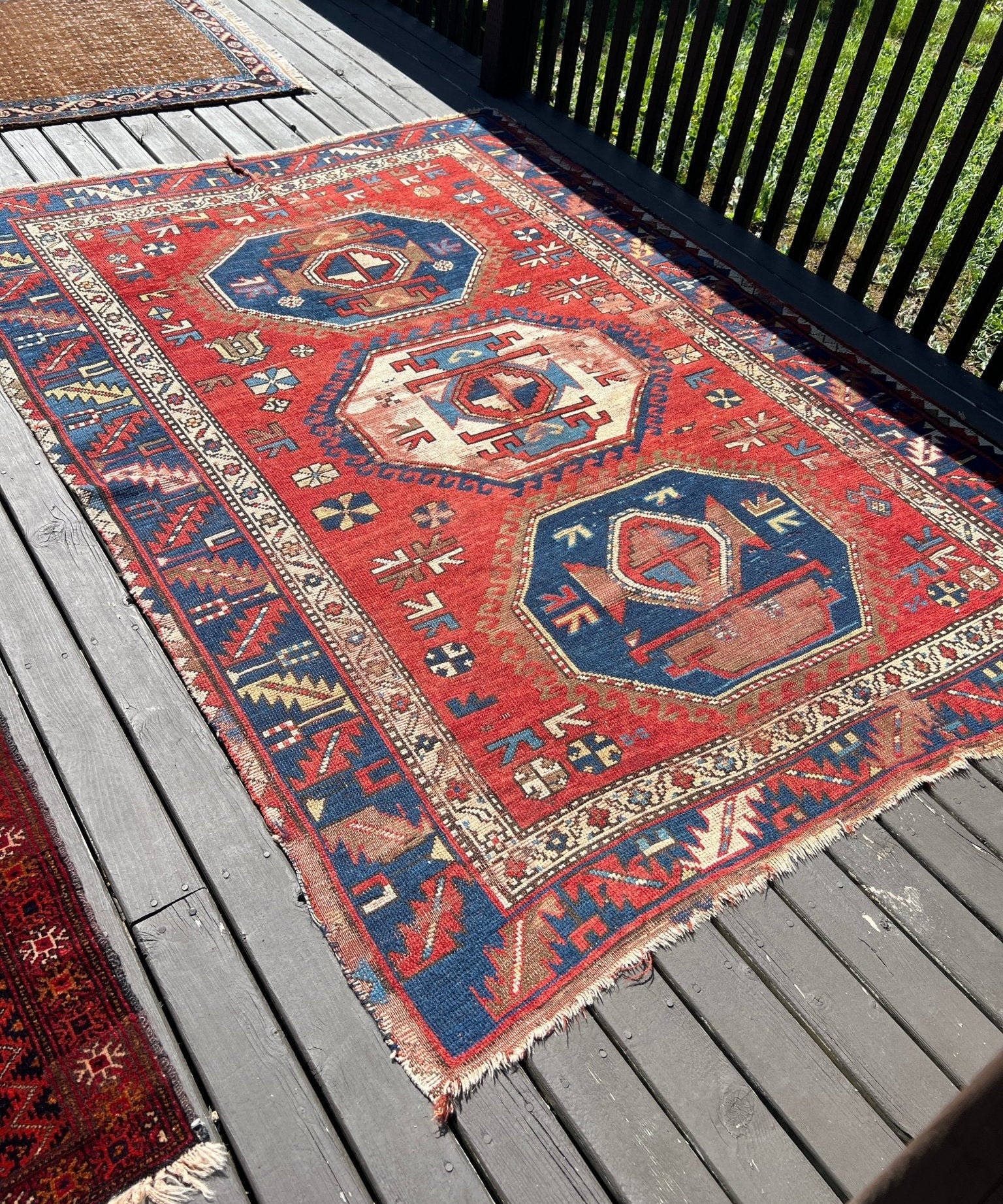 Antique red, blue and cream geometric wool rug with ornate border and small medallions.