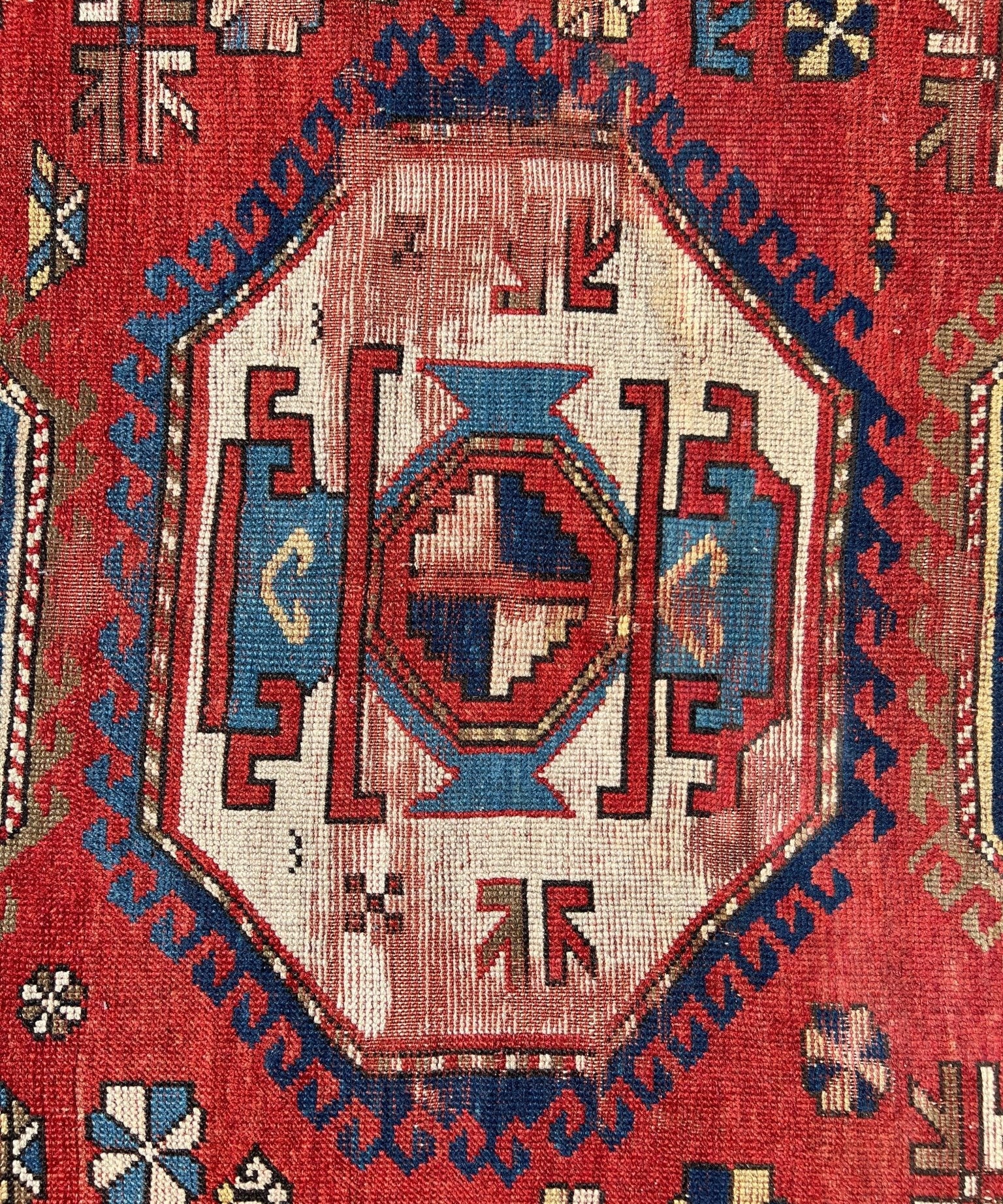Antique red, blue and cream rug featuring a central hexagonal medallion design.