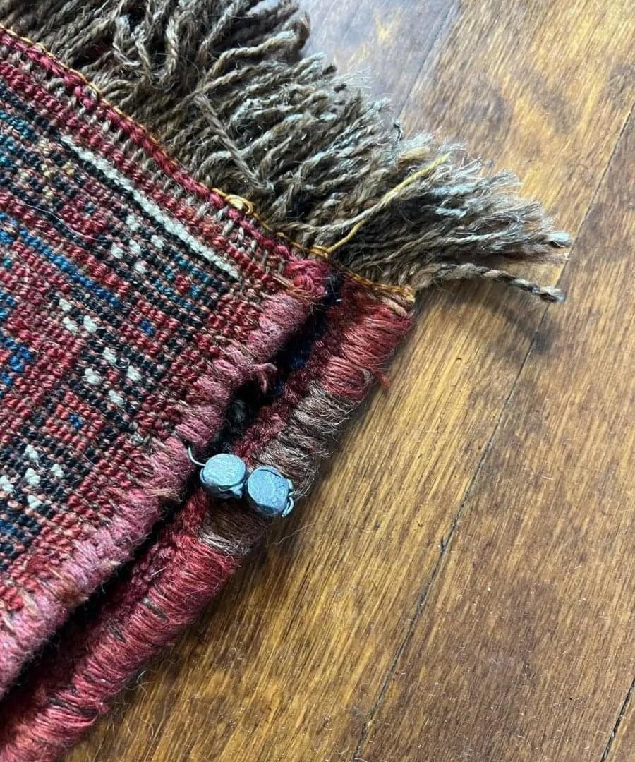Antique Khamseh rug corner with fringed ends and red woven trim, stitched edge