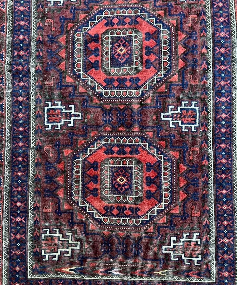 Persian Baluch rug with repeating red and navy lozenges, cream medallion panels