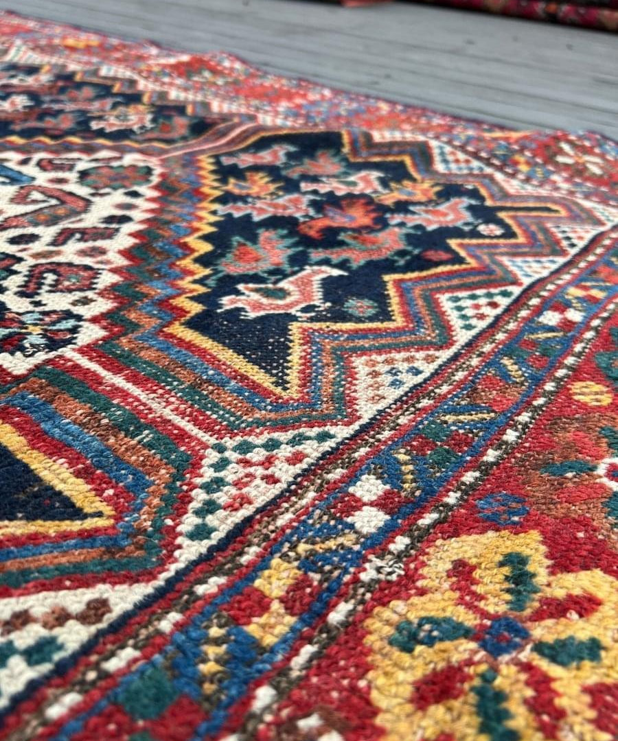 Antique Persian Khamseh rug corner close-up with navy zigzags and red edging