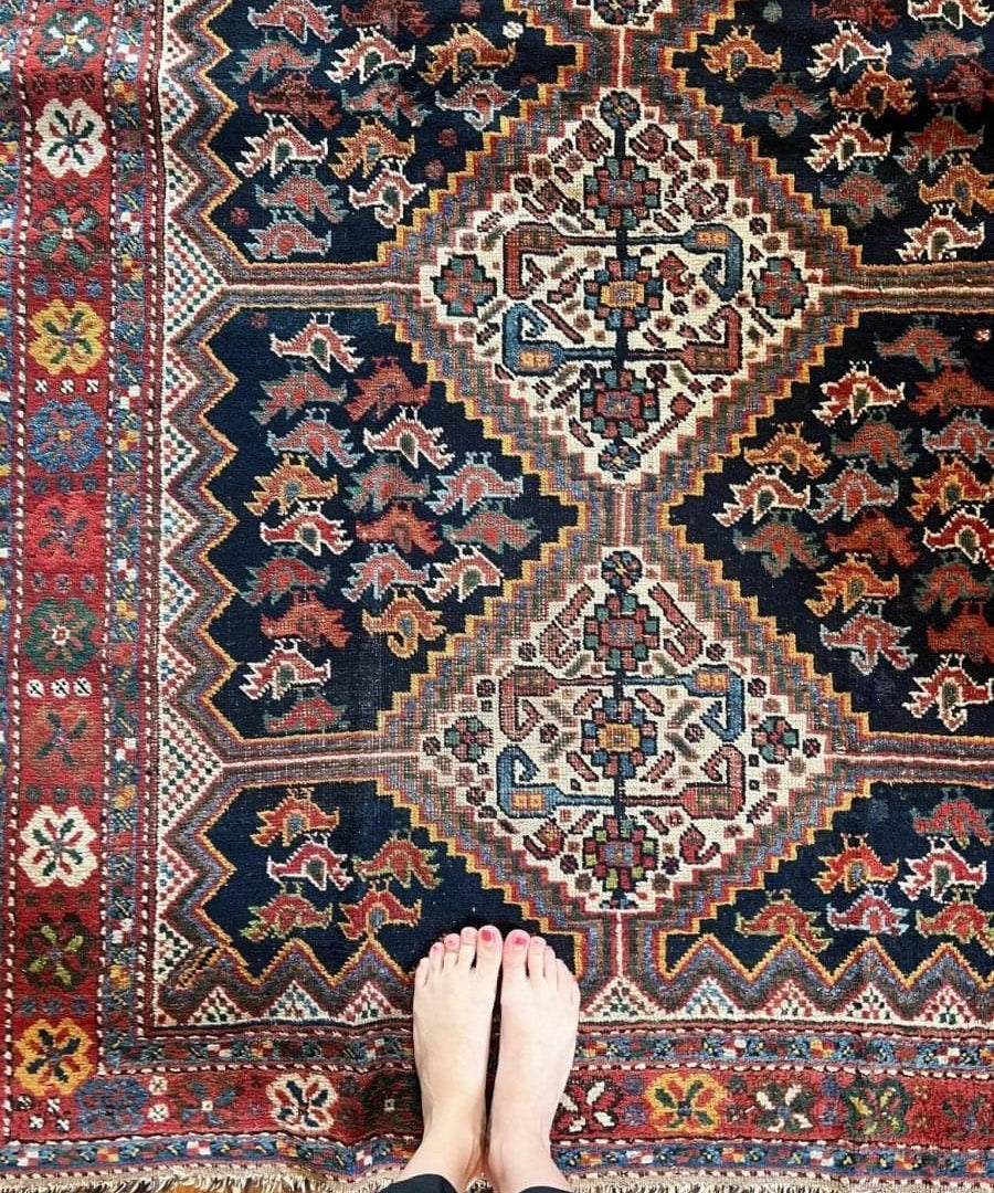 Antique Persian Khamseh rug close-up with navy field, red accents, and cream motifs