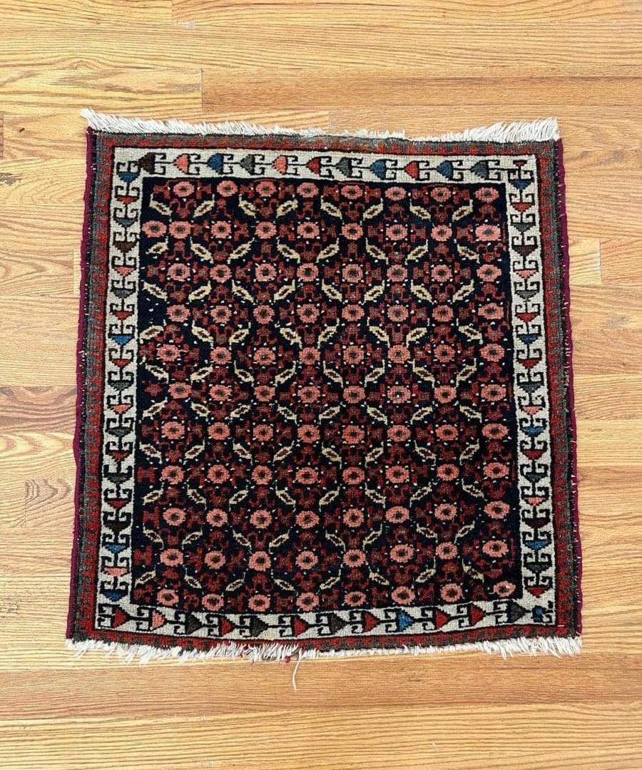 Persian Malayer rug with dark navy field, red floral medallions, and Greek-key border.