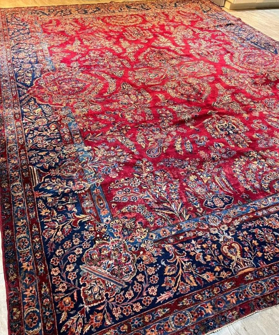 Antique Persian Sarouk rug with red center, blue border, and scrolling vine motifs