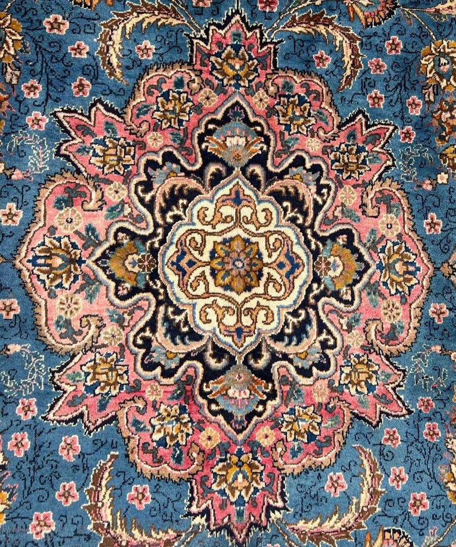 Persian Kashmar rug close-up, blue background with colorful floral medallion motifs