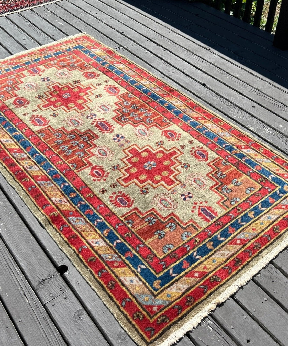 Small rectangular rug with red, cream, blue geometric medallion pattern and fringe edges