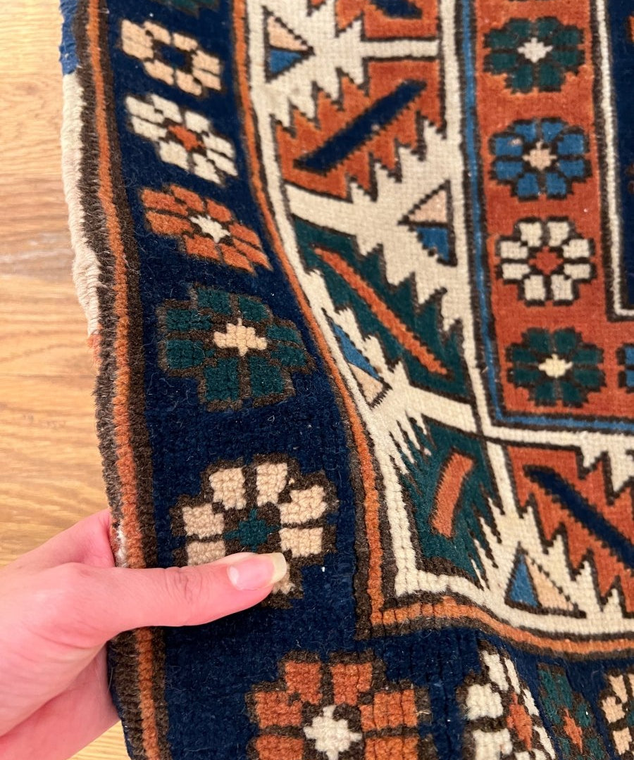 Fringed edge of a Central Anatolian rug with navy, rust, teal and cream geometric pattern