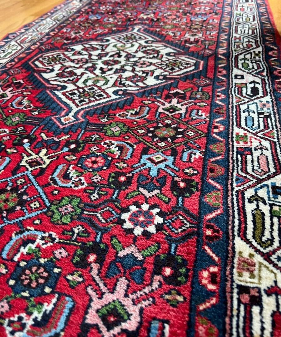 Close-up of red and navy runner rug corner with white and green details
