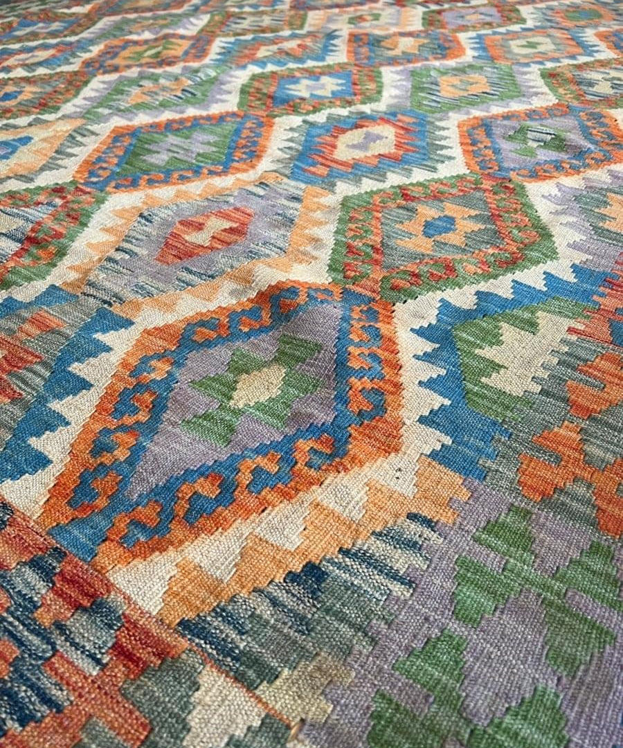 Close-up of multicolor geometric kilim rug with textured weave and diamond motifs.