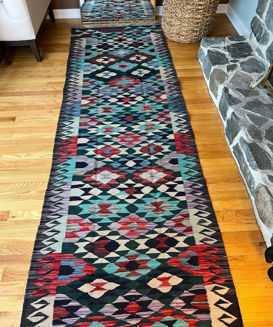 Narrow kilim runner rug with geometric diamond bands in red, teal, cream on dark navy