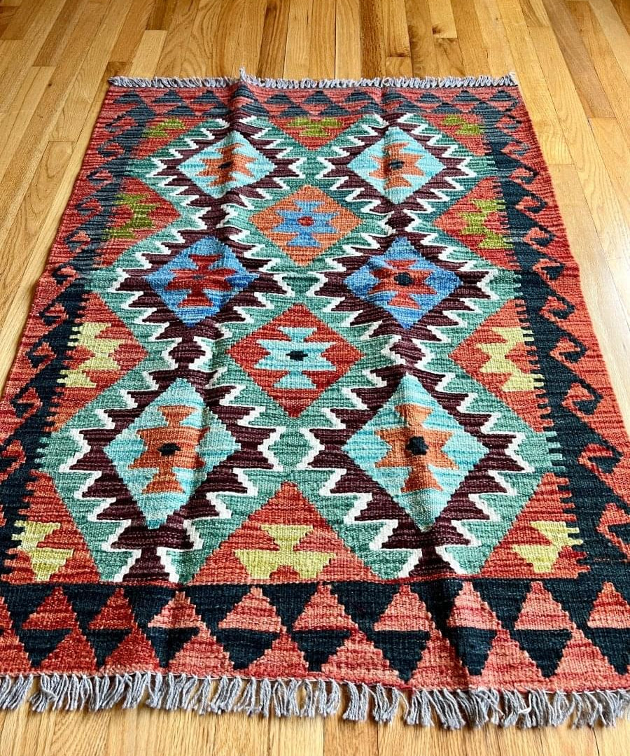 Kilim rug with central diamond medallion, colorful geometric pattern, and fringe trim