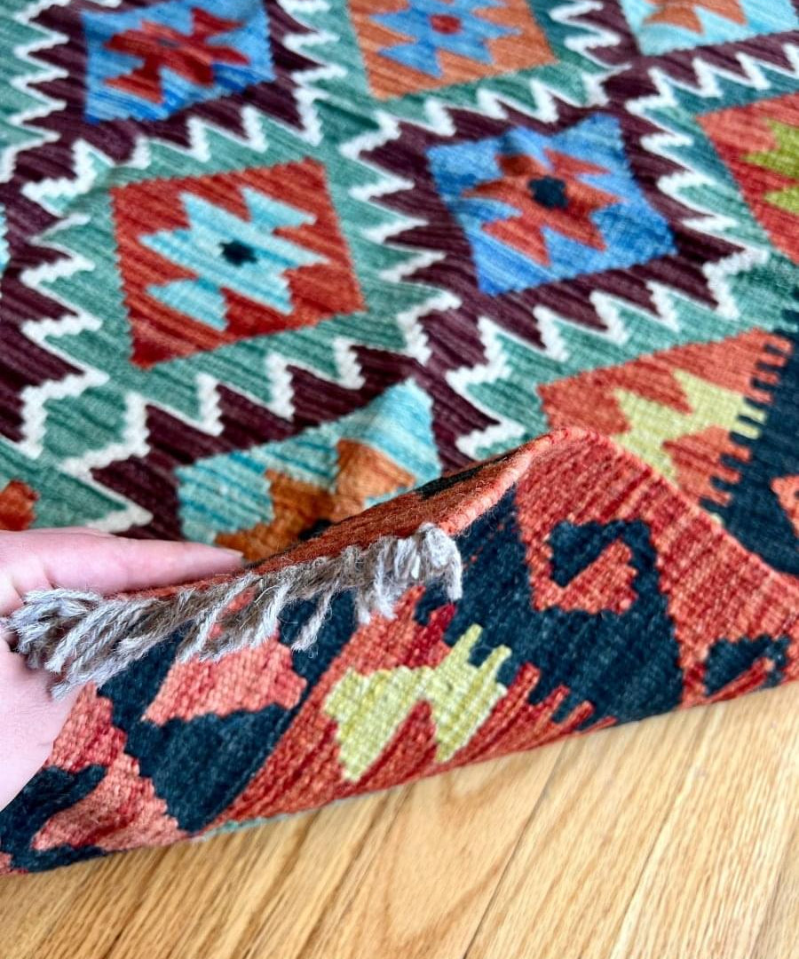 Multicolor kilim rug close-up with zigzag diamonds and visible textured fringe