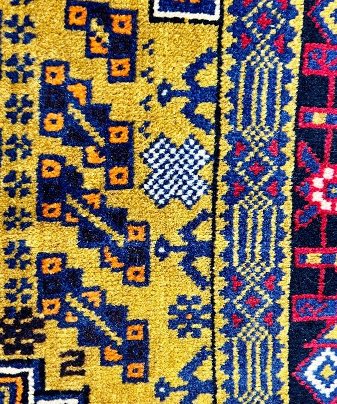 Vintage Afghan Baluch rug close-up with blue and yellow geometric motifs