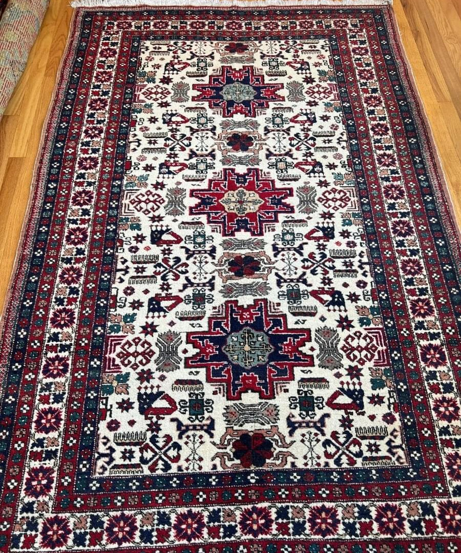 Persian-style area rug with ivory center, dark navy-red border, geometric motifs