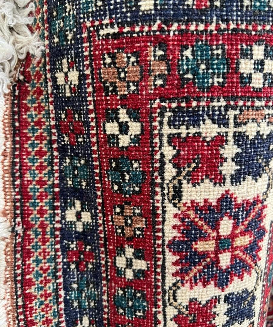 Close-up of Persian rug border with red, teal, and navy geometric pattern