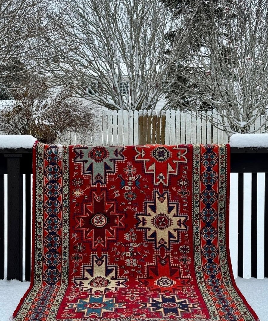 Red geometric rug with blue side panels, central medallions, and fringed border
