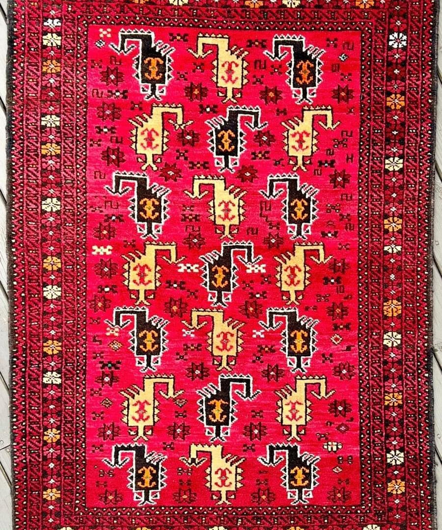 Persian Baluch rug with red field, navy border, geometric motifs and central medallion