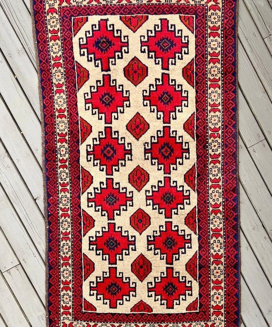 Persian Baluch rug, ivory with red and dark blue geometric medallions and border