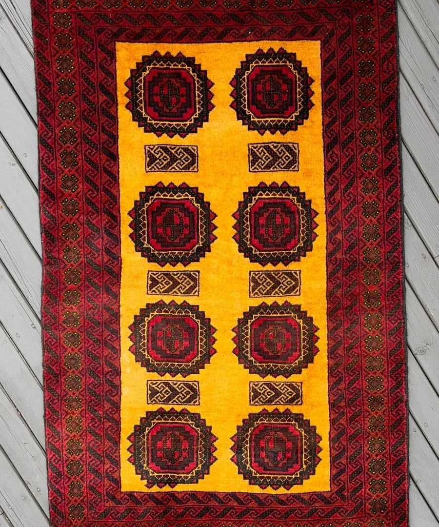Persian Baluch rug with cream field, burgundy border, dark blue medallion motifs.