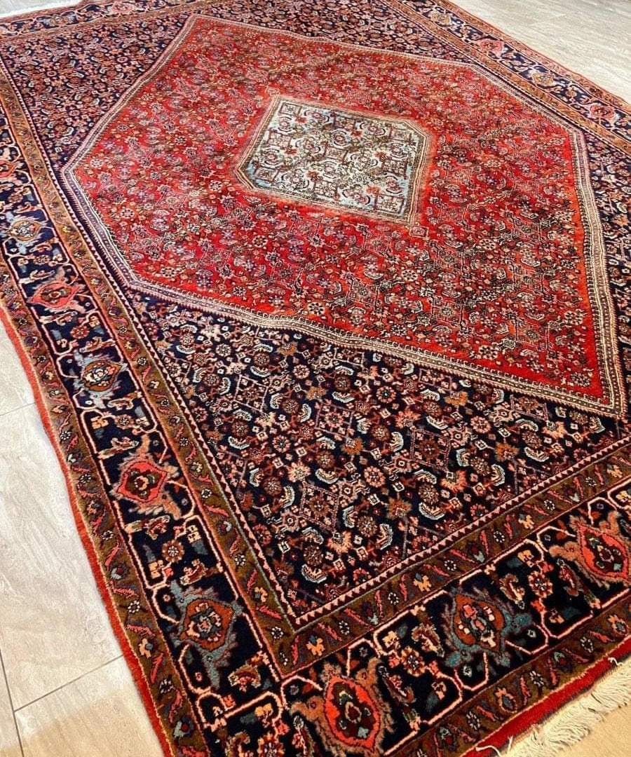 Persian-style area rug with red medallion, navy floral field, cream border