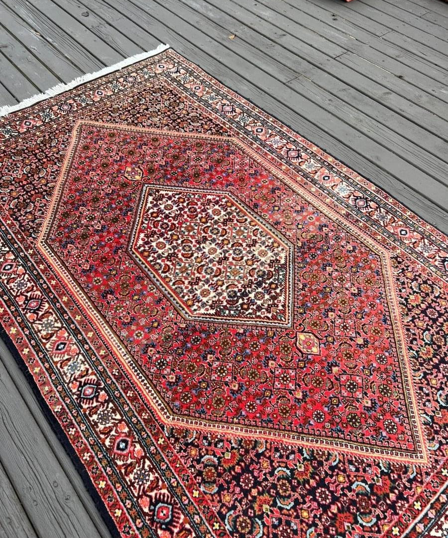 Red Persian-style bidjar rug close-up with intricate geometric motifs and inner diamond medallion.