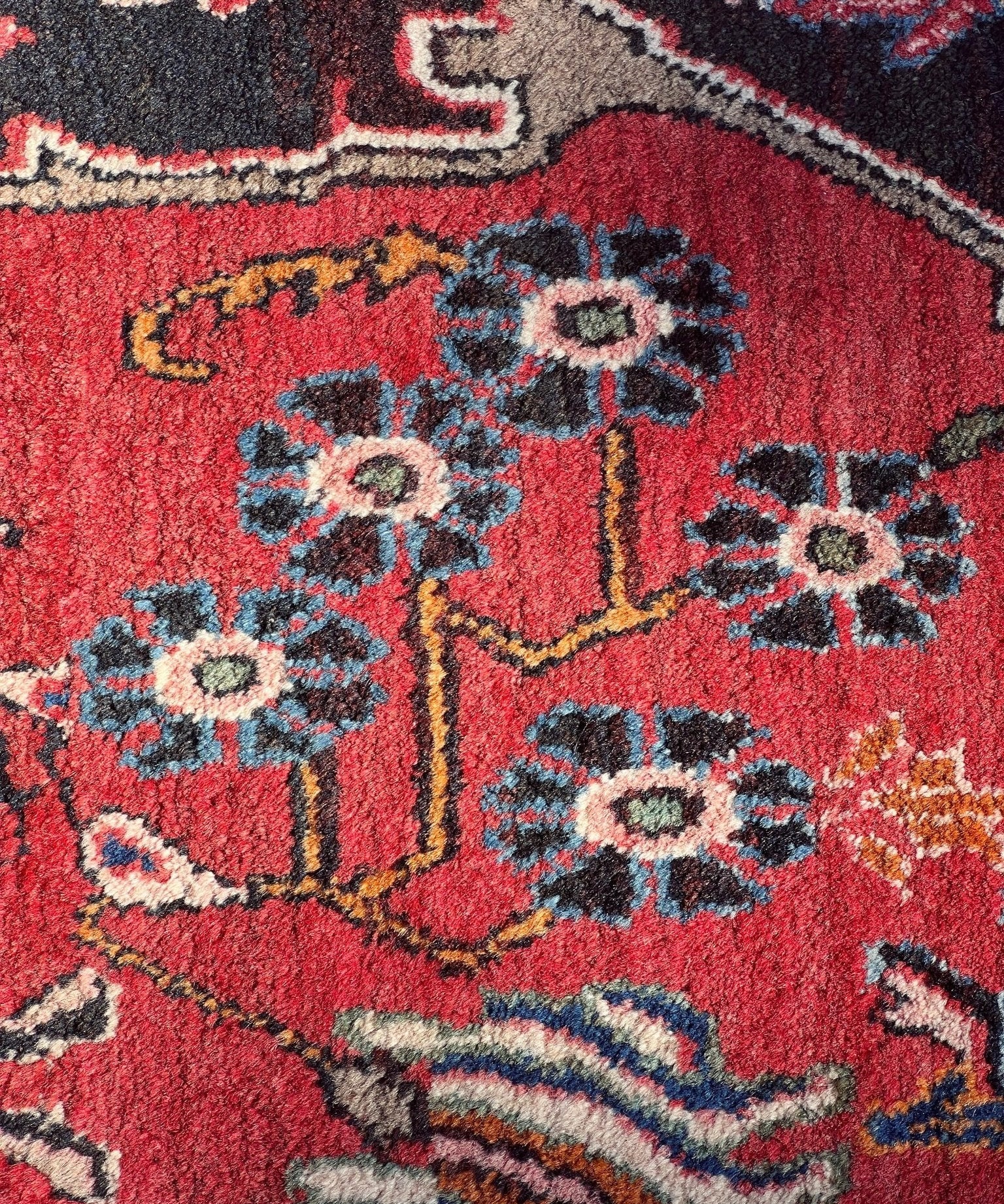 Close-up of red rug with blue floral motifs and geometric border