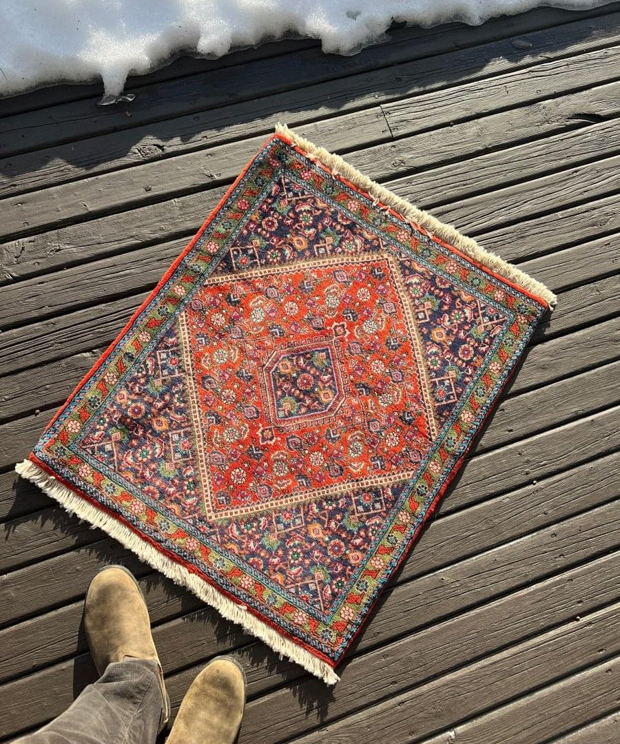 Red Persian mini rug with ornate center medallion, navy teal border, short fringes