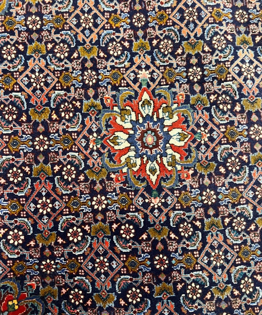 Close-up of Bijar rug floral motifs in navy, red, and cream with ornate details