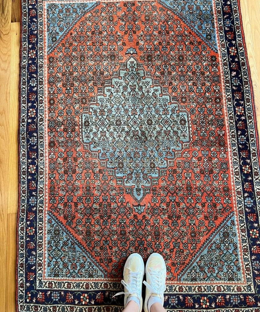 Persian Bijar rug with central light medallion, rust-orange field, and dark blue border