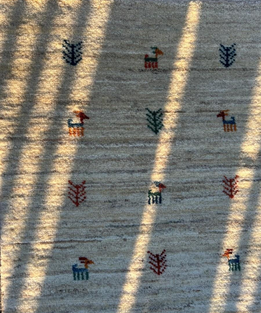 Gabbeh-style runner close-up: light gray-blue with multicolor animal icon pattern