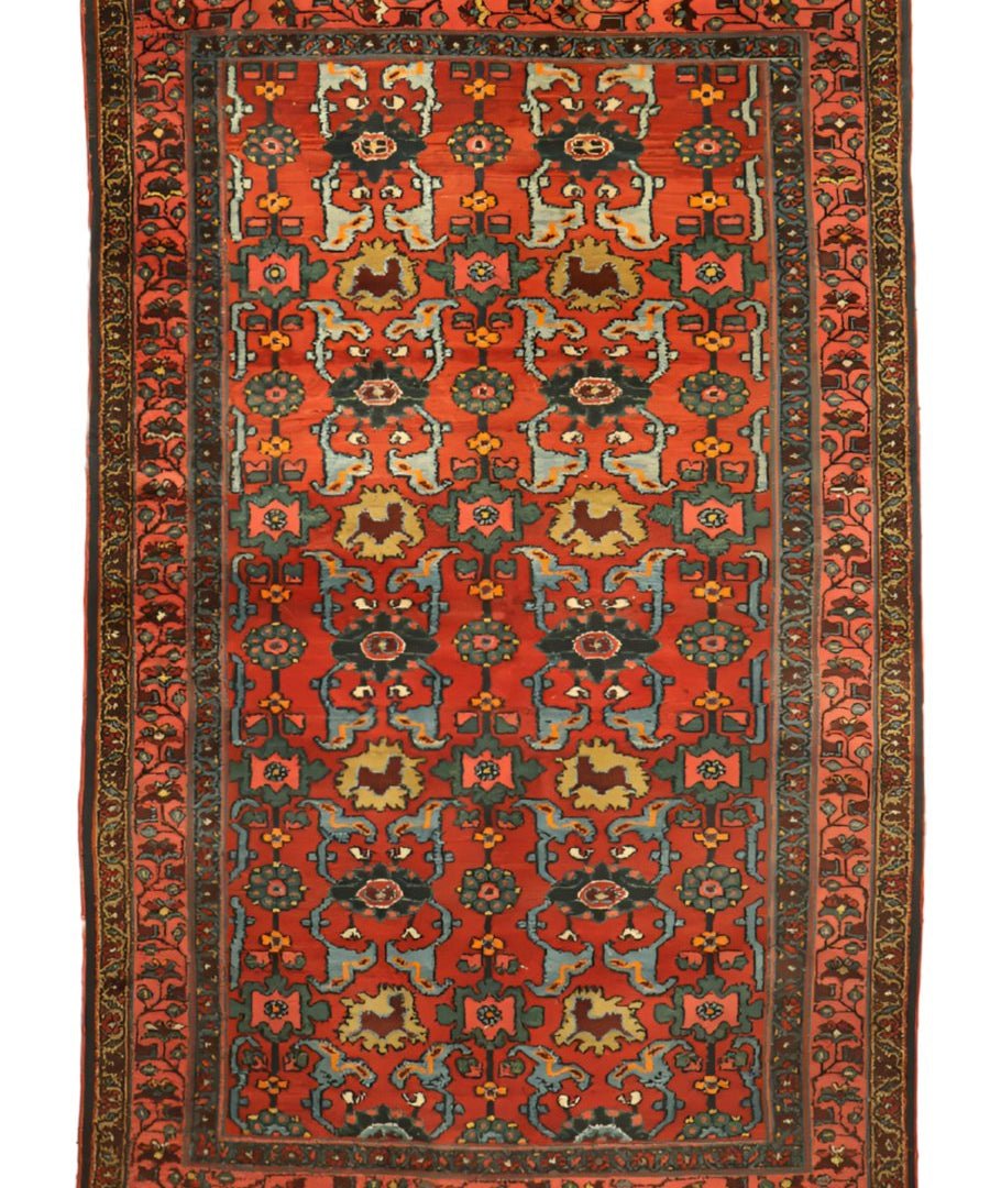 Orange-red rug with multicolor geometric medallions and ornate border, flat-lay