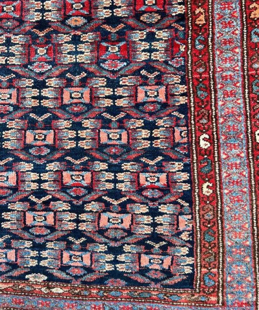 Persian Hamadan rug close-up of blue field with red border and repeating geometric motifs