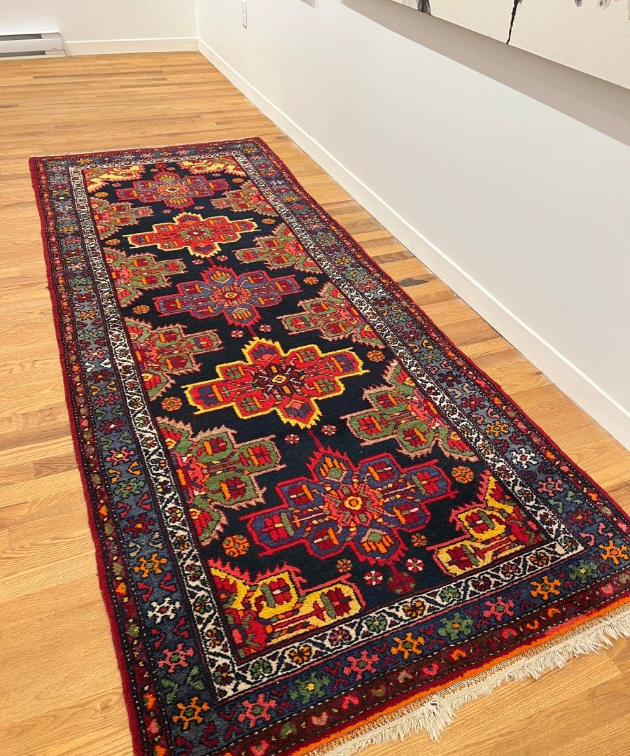Persian runner rug with navy field, red medallions, and cream fringe border