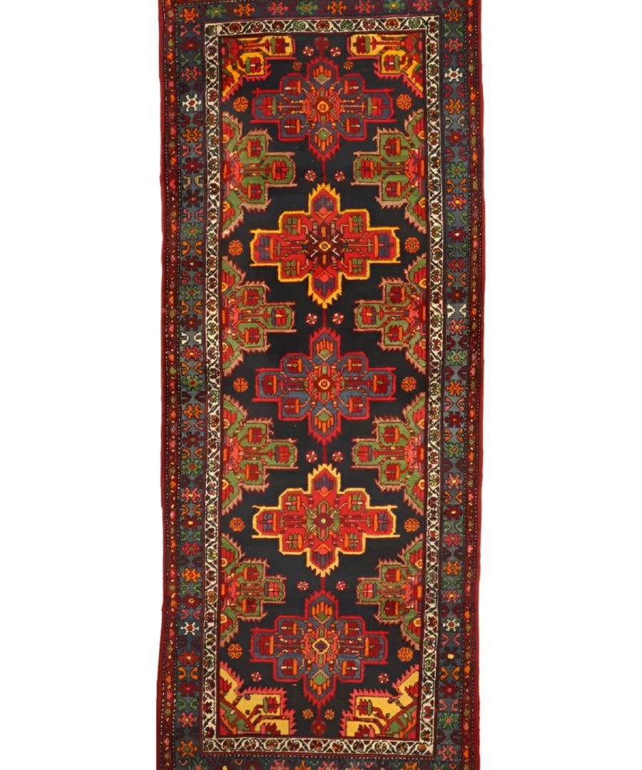 Persian runner rug with dark navy field and red, green, and gold central rosette