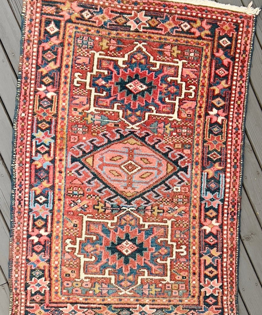 Persian Karaja rug with central red medallion, teal and beige geometric border.