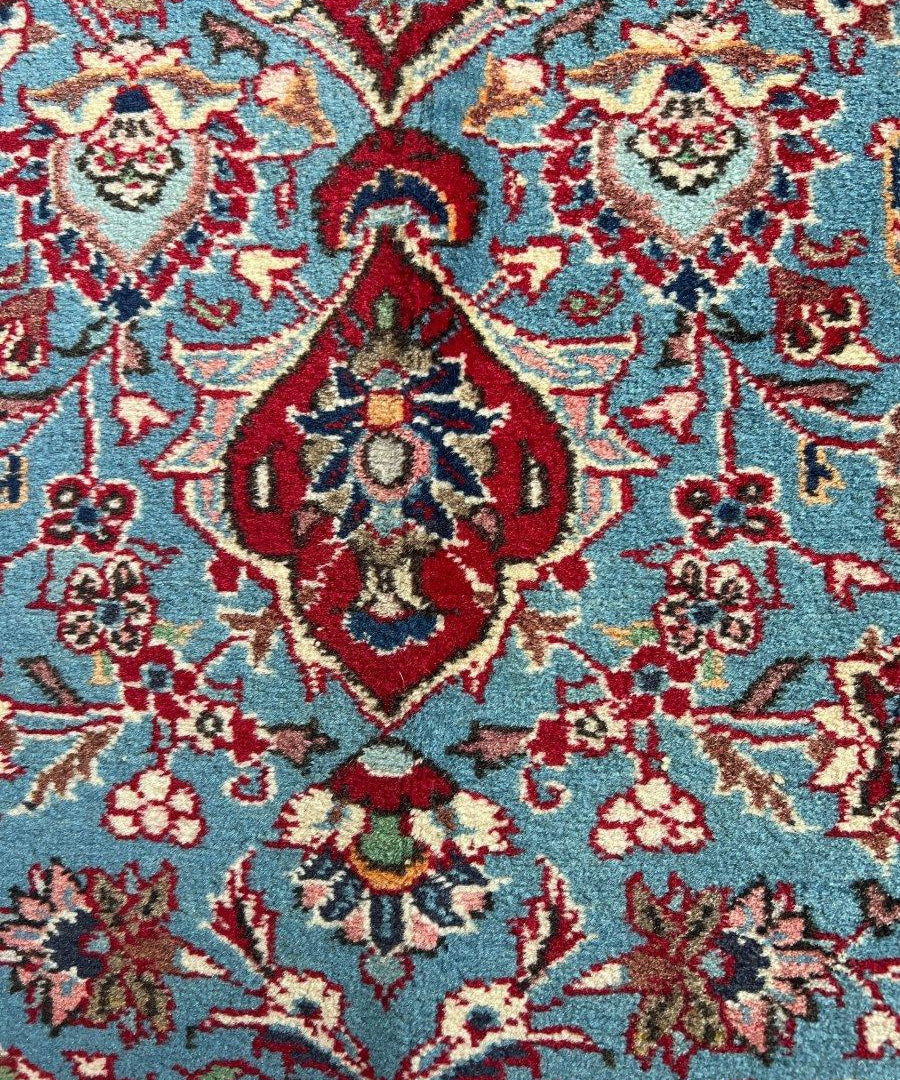 Blue rug section with red floral vines, repeating ornaments, and central decorative motif