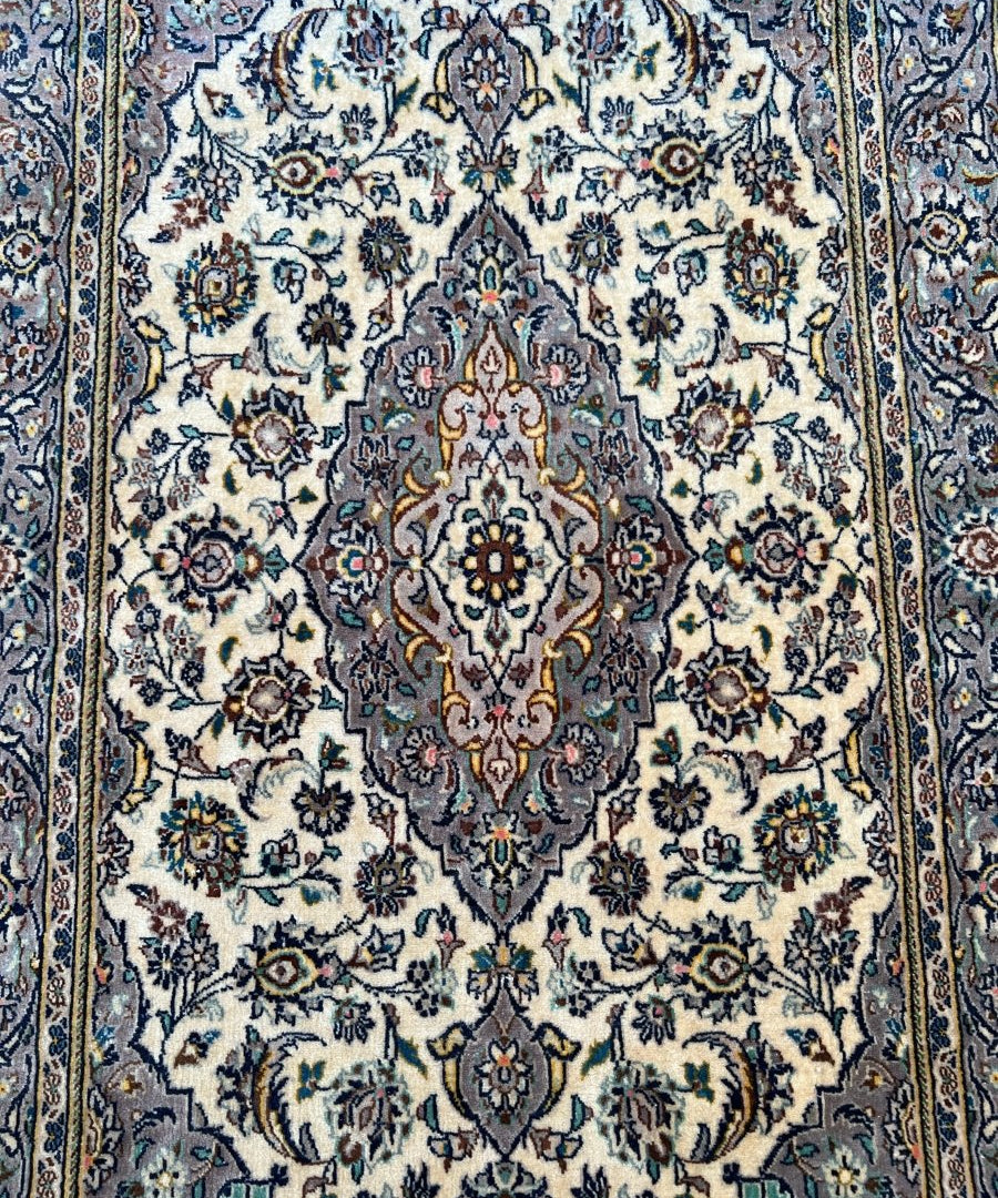 Persian Kashan rug close-up with cream field, navy and teal floral details
