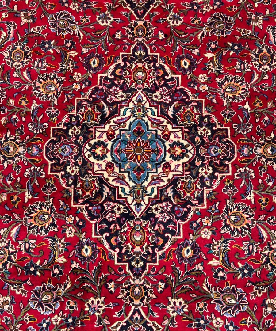 Persian Kashan rug close-up of red floral pattern with navy accents and cream details
