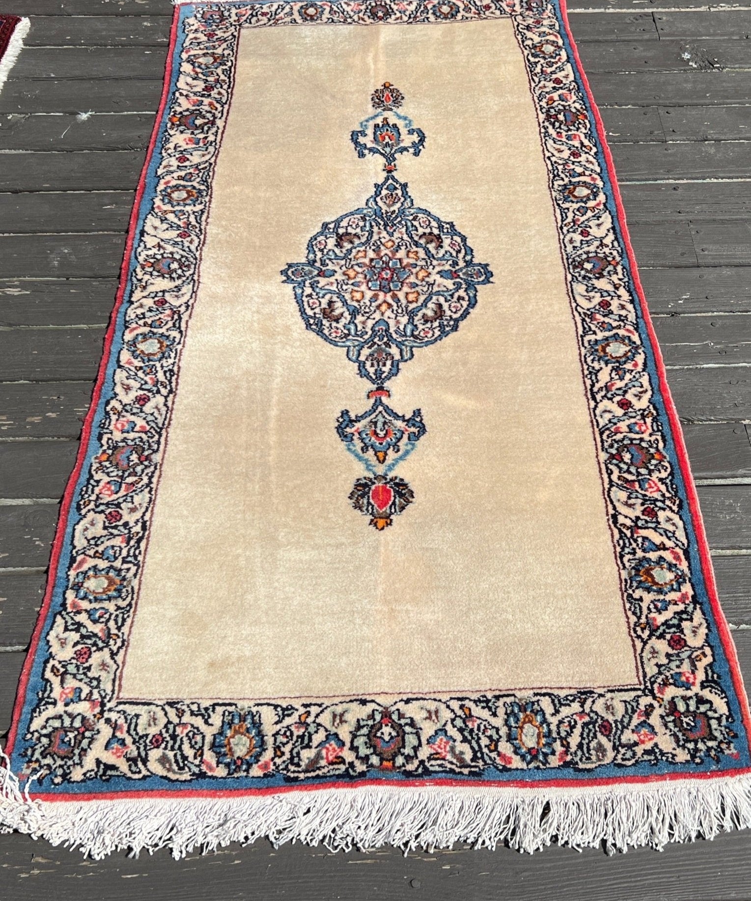 Cream Persian Kashan rug with blue and red medallion, navy border, short fringe