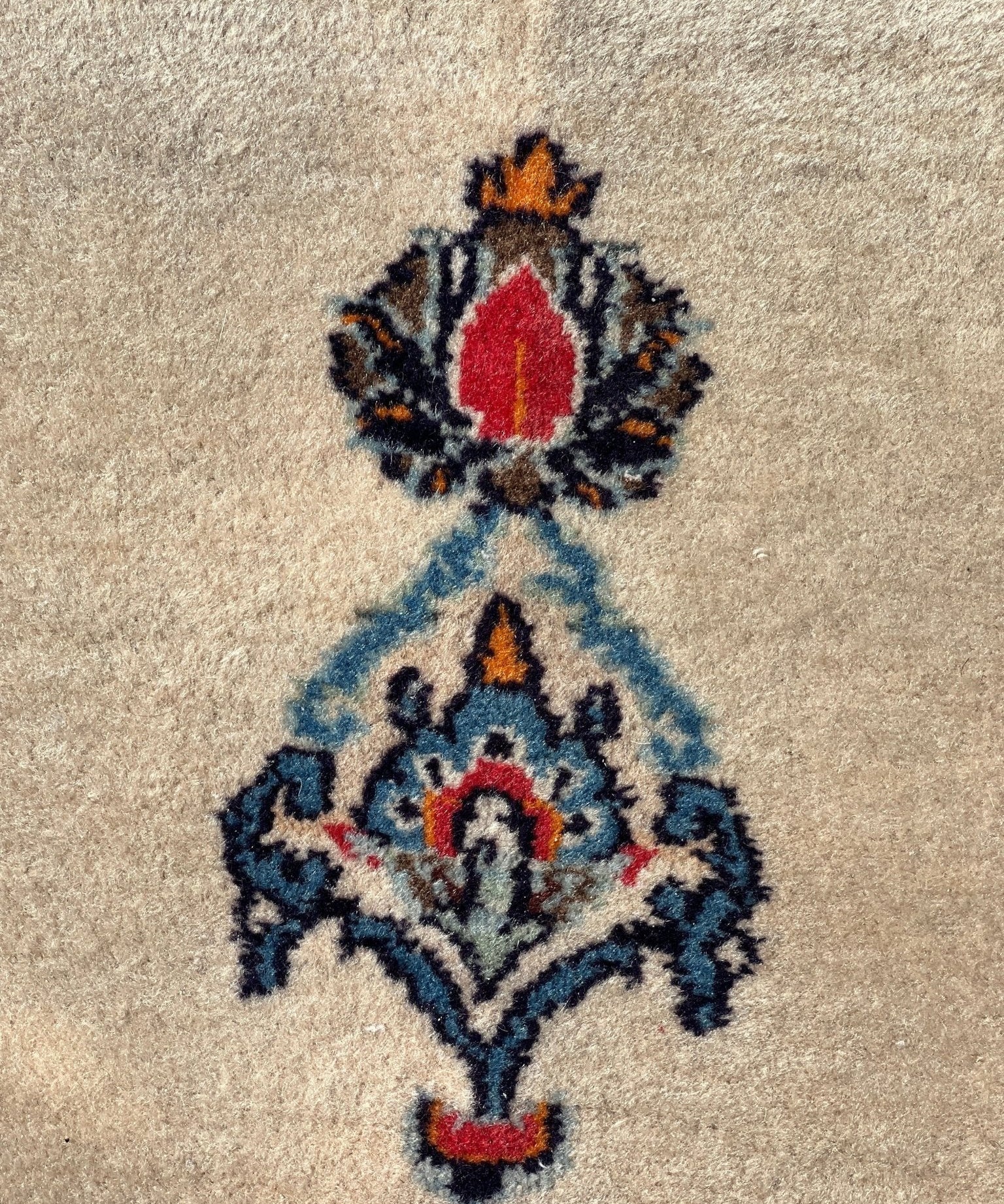 Close-up cream rug with blue floral motif and red accents, textured wool pile