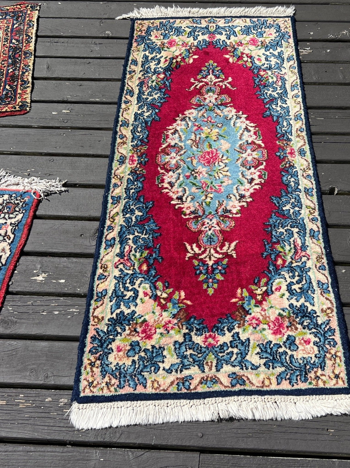 Small floral Kerman rug catalogued by Rug the Rock as circa 1920, photographed on a deck